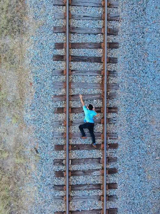 Una foto de un hombre en las vías del tren, tomada desde arriba para dar la ilusión de que está subiendo