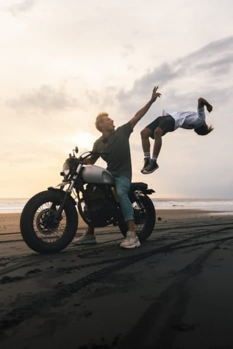 Foto de un chico en una motocicleta con un chico saltando de ella