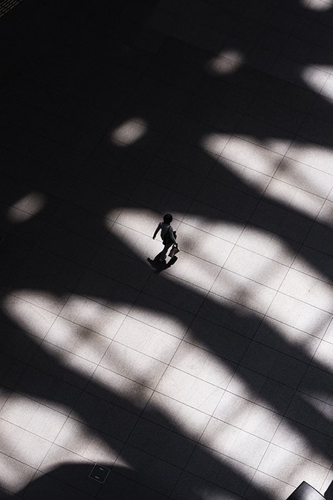 Foto aérea de una persona caminando entre sombras pesadas en un camino de piedra - fotografía de forma