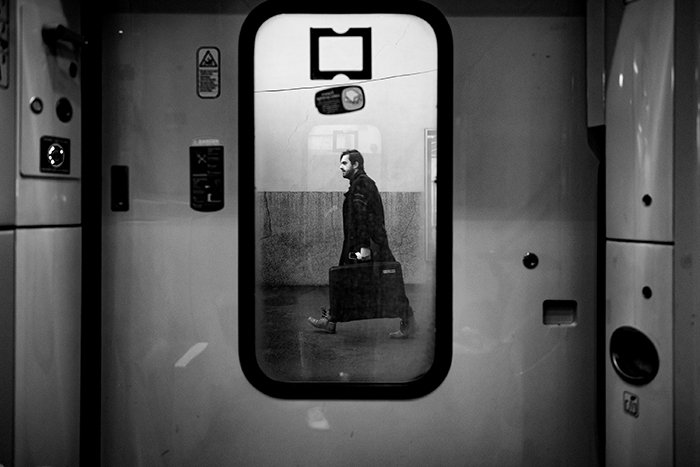 Foto de un hombre caminando con una maleta reflejada en un espejo