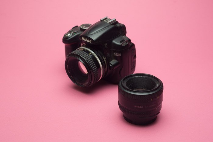 Una lente Nikon DSLR sobre fondo rosa bebé