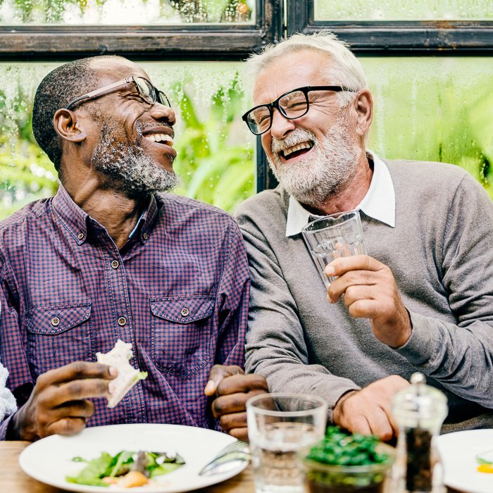 retrato de dos amigos varones riéndose durante la cena