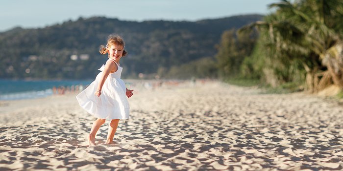 una niña corriendo en la playa, su acción congelada en movimiento