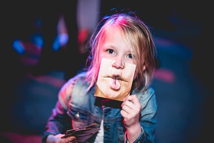 Un retrato fotográfico divertido de un niño sosteniendo una foto de una boca divertida para sí mismo