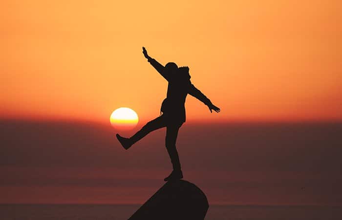 La silueta de una persona balanceándose en un rosa frente a una hermosa puesta de sol