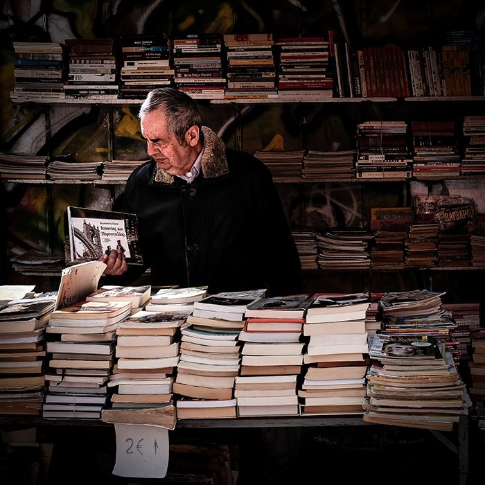 Un retrato callejero de un hombre hojeando libros en un mercado al aire libre - fotografía de la teoría de la gestalt