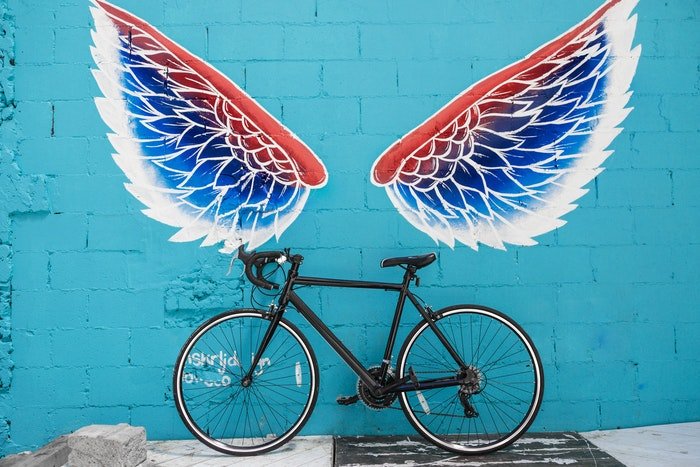 Una bicicleta apoyada contra una pared pintada