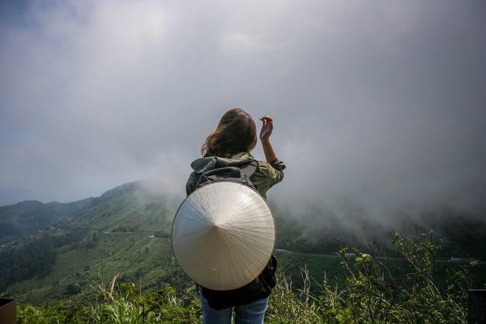 Una niña se para frente a un paisaje montañoso.
