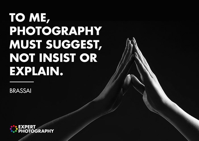 Un primer plano en blanco y negro de dos manos tocándose superpuesto con una cita de Brassai sobre lo que hace una buena fotografía