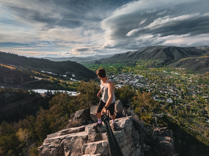 Un hombre en una montaña tomándose una foto con un palo selfie
