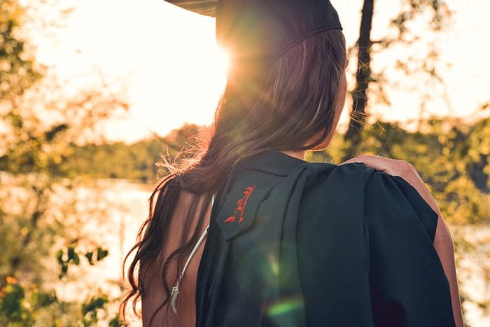 Hermoso retrato sincero de graduación de una estudiante al aire libre en un bosque