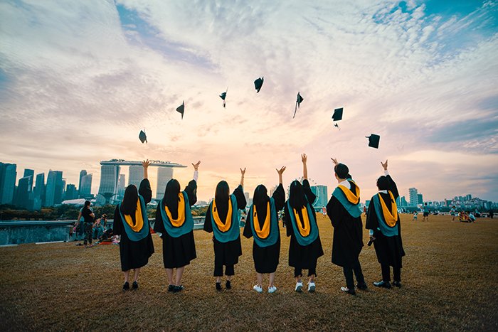 Un grupo de estudiantes de graduación lanzando sus sombreros al aire - fotografía de graduación