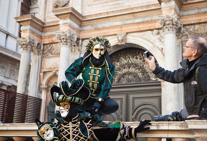 El hombre que toma una foto de dos actores es máscaras y disfraces, actuando frente a una antigua estructura histórica