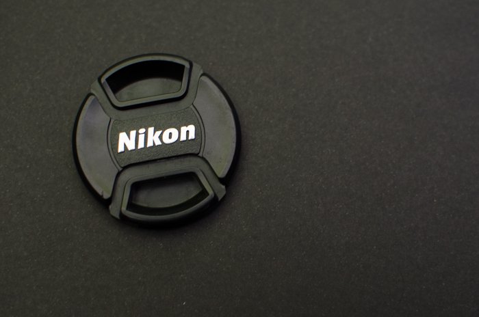 Una tapa de lente Nikon sobre fondo gris: cómo usar una tarjeta gris para equilibrar el color