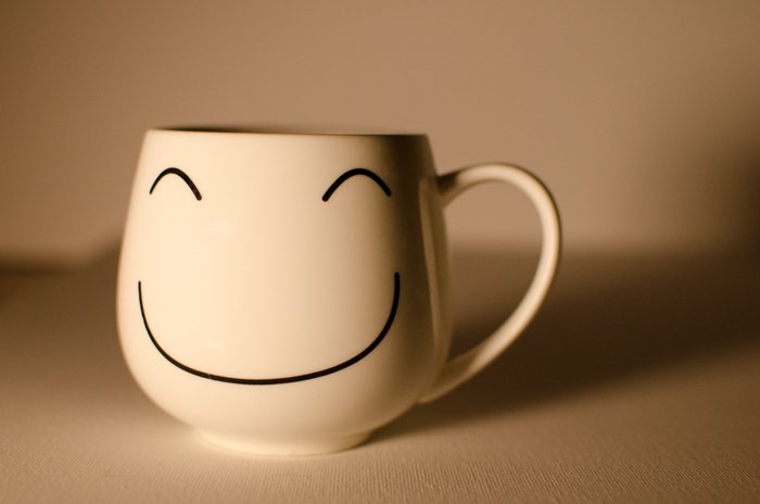 Una taza con una carita sonriente sobre un fondo neutro: cómo usar una tarjeta gris para equilibrar el color