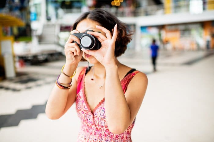 Una fotógrafa sosteniendo una cámara compacta contra un fondo borroso - cámaras del mercado gris