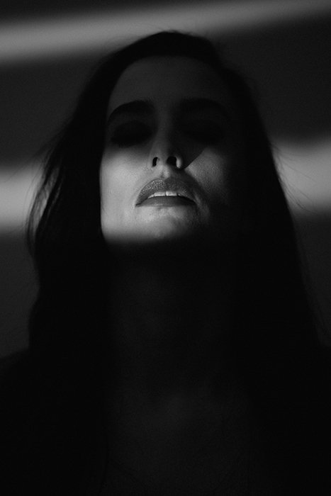 Retrato de fotografía de cine negro de una modelo femenina cuyos ojos están naturalmente ocultos por sombras oscuras para crear una atmósfera espeluznante e intrigante.