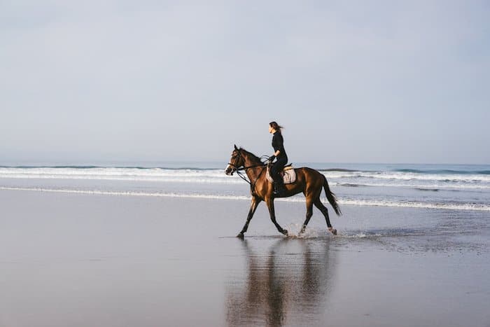 Imagen de una mujer montando a caballo en una playa usando la regla de los tercios