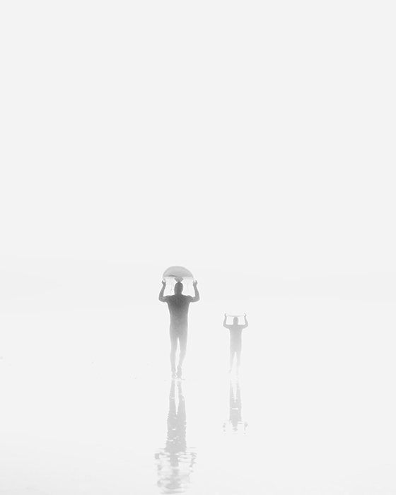 Retrato atmosférico de las siluetas de un adulto y un niño caminando con algo sobre sus cabezas
