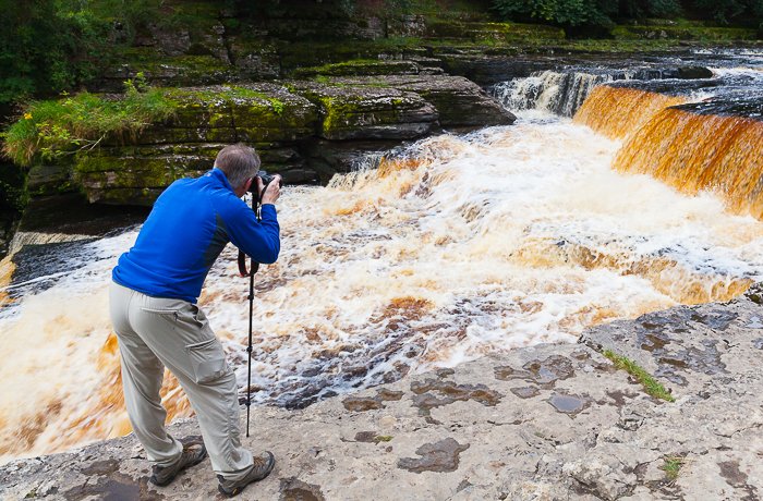 un fotógrafo que intenta una fotografía de movimiento congelado de una cascada