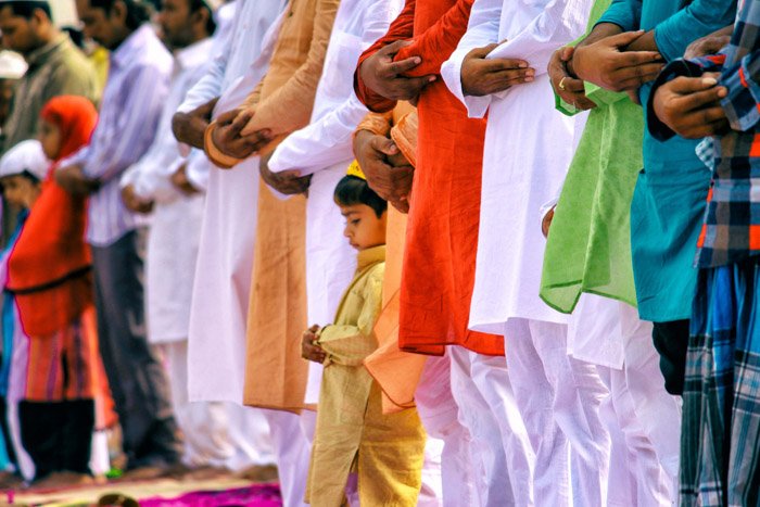 Una multitud de personas con los brazos cruzados en oración, centrada en un niño