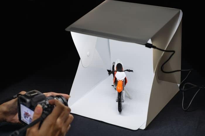 una persona fotografiando un producto pequeño en una caja de luz