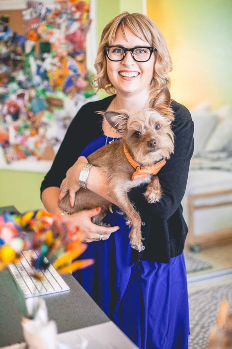 Una foto divertida y colorida de una mujer posando en el interior con un perro pequeño