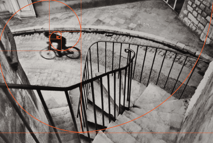 un henri cartier bresson en blanco y negro de un ciclista fotografiado desde arriba con superposición de espiral de fibonacci