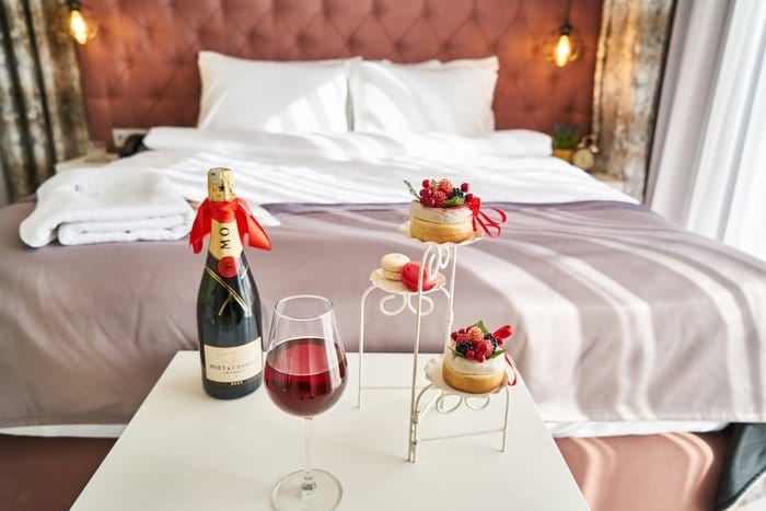 Champán y pasteles a los pies de una lujosa cama de hotel