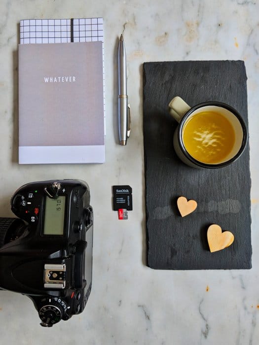 Fotografía de bodegones aéreos de una cámara, un portátil, un bolígrafo, una taza de café y una tarjeta de memoria