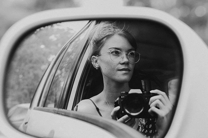 autorretrato creativo en blanco y negro de una mujer joven en el espejo de su auto