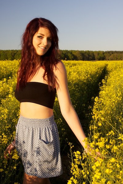 Una mujer con falda sonriendo en un campo de flores.