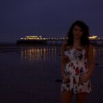 Fotografía de retrato de una niña de pie en una playa.  Fotografía crepuscular.