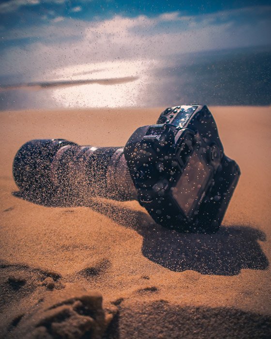 Una cámara DSLR descansando en la arena de la playa.