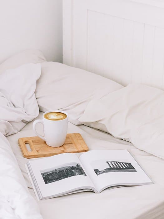 Una naturaleza muerta artística de un fotolibro y una taza de café en una cama: cómo hacer tu propio fotolibro para hacer tu propio fotolibro