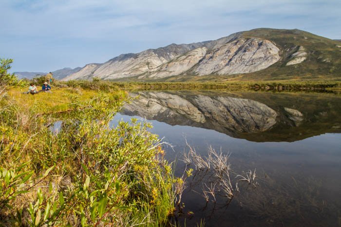fotografiando junto a un lago en el Parque Nacional Gates of the Arctic, Alaska en un día muy brillante, los reflejos en el estanque reflejan las montañas.