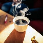 Una taza blanca de café caliente rodeada de vapor: cómo fotografiar el vapor del café