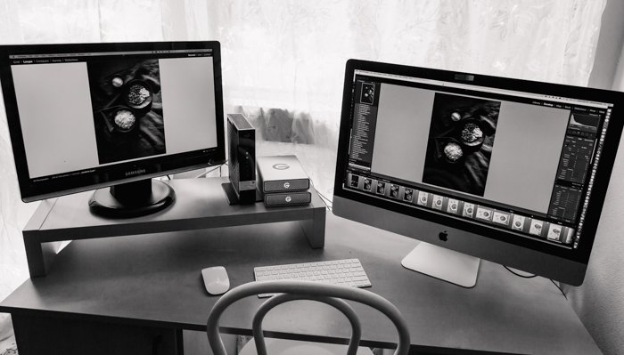 la oficina de un fotógrafo con dos pantallas de portátiles abiertas en un programa de edición que muestra cómo imprimir fotografías de forma profesional 