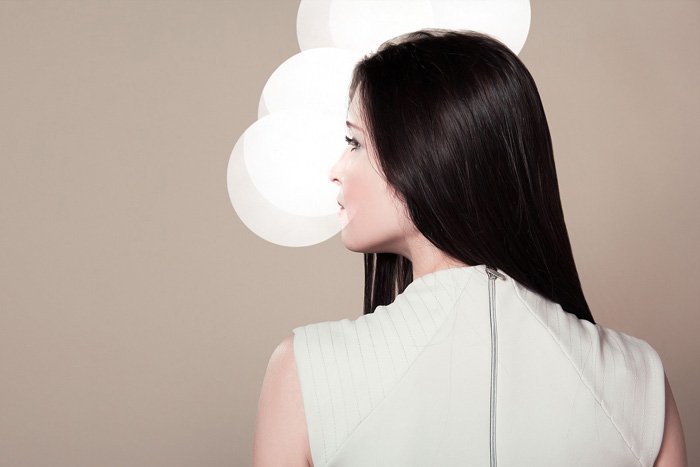 una modelo de moda femenina posando frente a un fondo beige limpio 