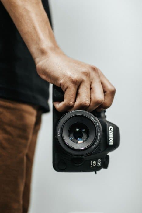 una imagen de primer plano de la mano de un hombre sosteniendo una Canon EOS 6D