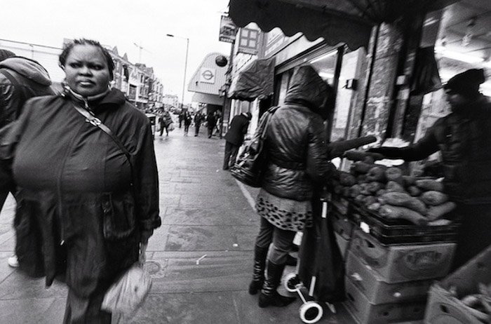 Una imagen en blanco y negro de personas caminando por un mercado al aire libre: fotografía desde la cadera