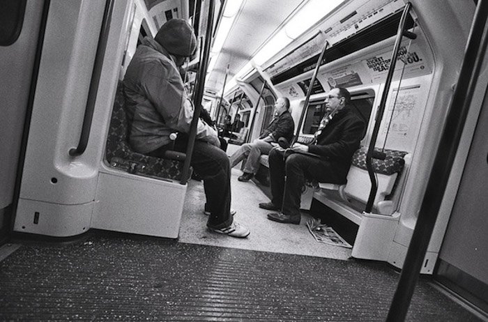 Una imagen en blanco y negro de personas en un metro: fotografía desde la cadera
