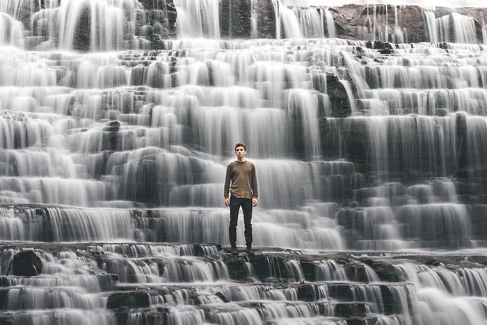 autorretrato creativo de un hombre parado en una cascada