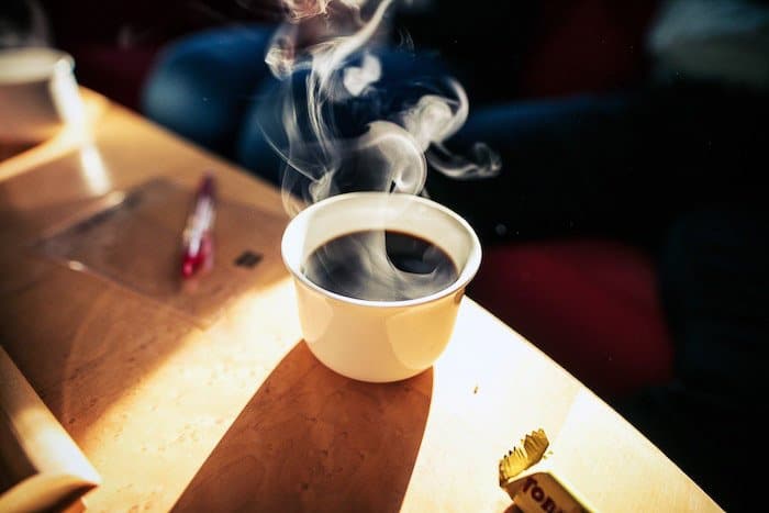 Una taza blanca de café caliente rodeada de vapor: cómo fotografiar el vapor del café
