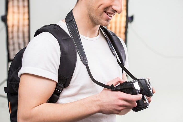 El joven fotógrafo con cámara en un estudio equipado profesionalmente está ajustando el flash de sincronización de alta velocidad en su cámara DSLR