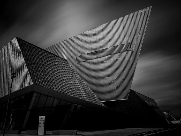 Fotografía en blanco y negro del nuevo centro de congresos en Mons, Bélgica, con cielo borroso