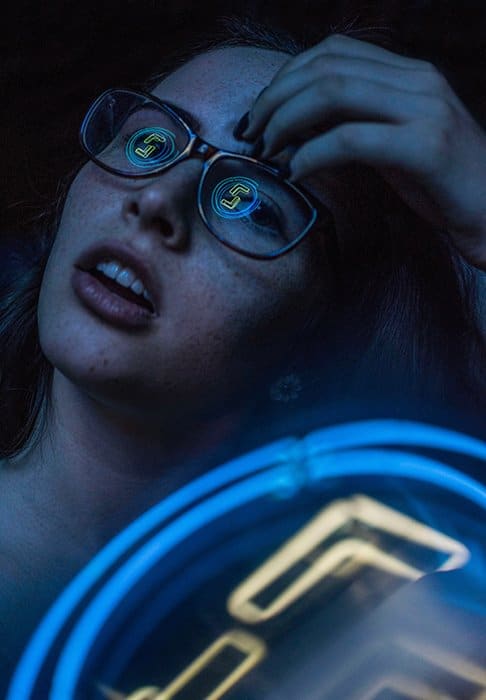Un retrato de fotografía de neón atmosférico de una modelo femenina con luces de neón reflejadas en sus gafas