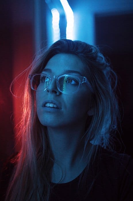 Un retrato de fotografía de neón atmosférico de una modelo femenina con luces de neón reflejadas en sus gafas