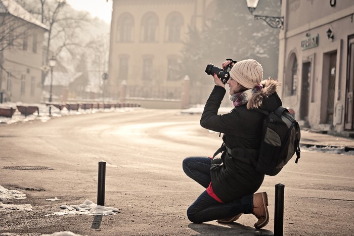 una fotógrafa filmando una escena callejera en una DSLR