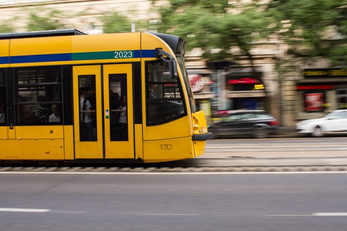 Una foto de un tranvía amarillo moviéndose en la calle.